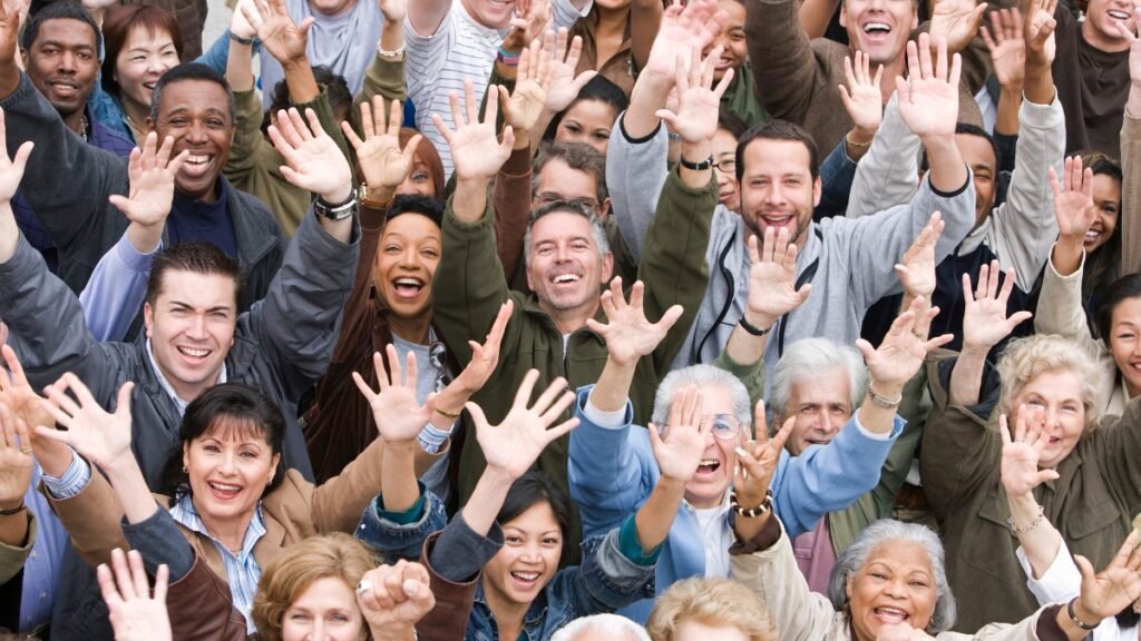 Diverse group of adults raising hands, representing the deconditioned market for personal training studios
