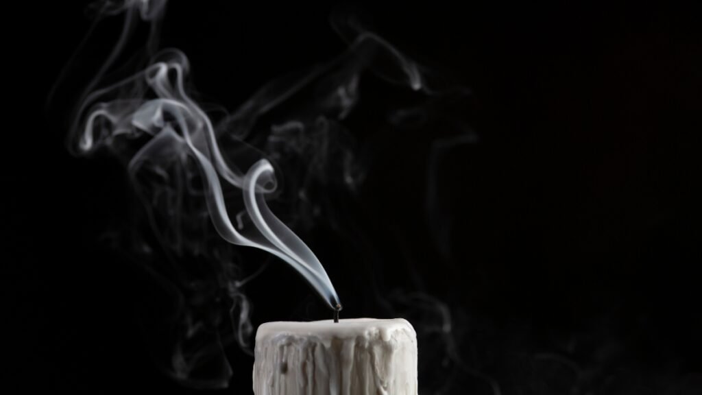 Extinguished candle with smoke on a dark background, symbolizing personal trainer burnout