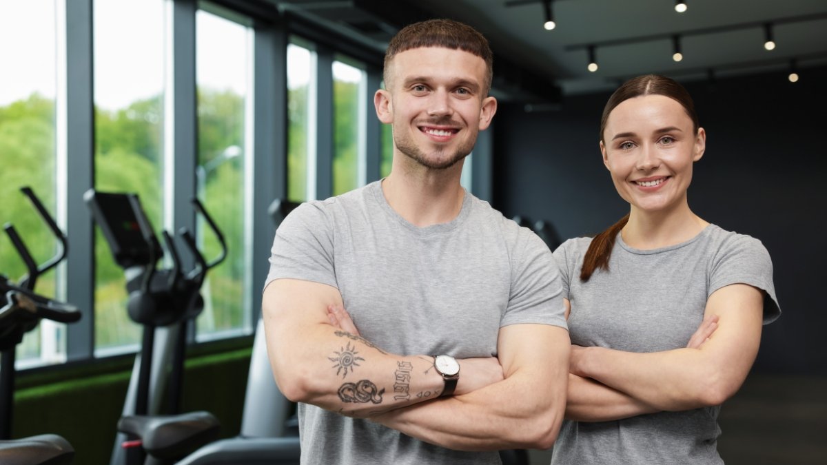 Two personal trainers standing in a gym, representing building a personal training business and studio ownership