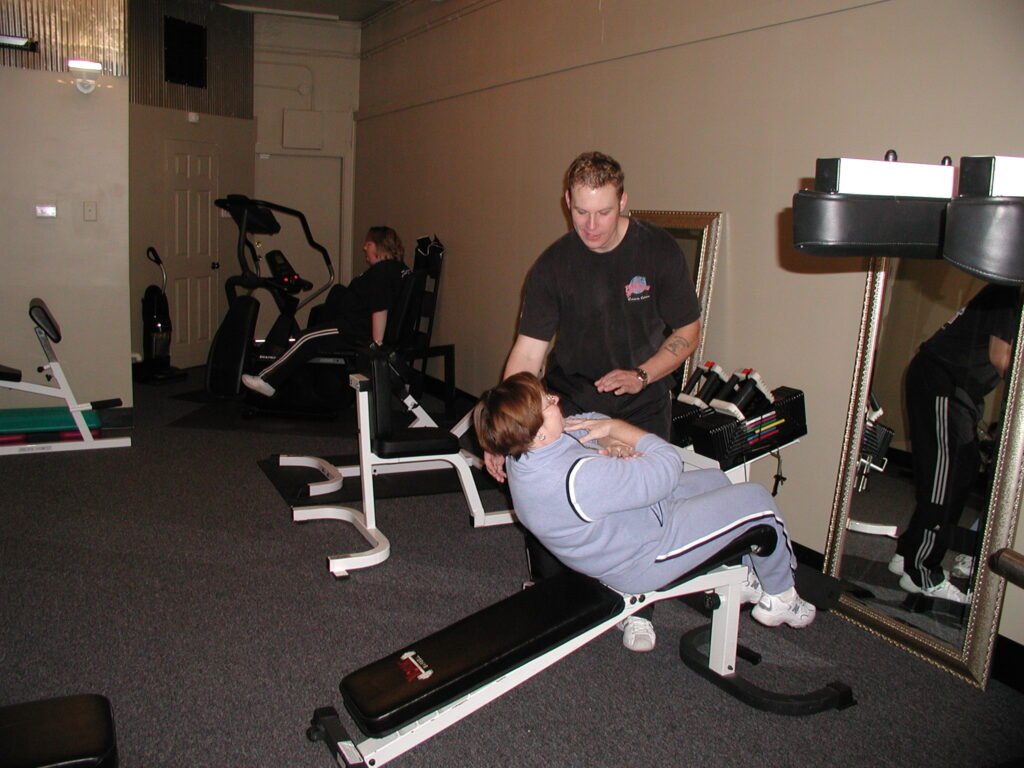 Personal trainer supervising a client during a strength exercise in a compact personal training studio